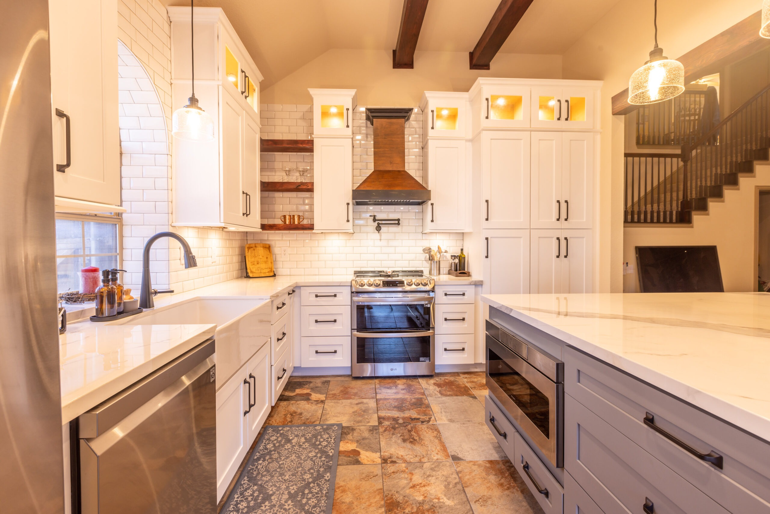 Modern kitchen featuring white cabinetry, a sleek stainless steel refrigerator, and a stylish gas range. Warm lighting enhances the inviting atmosphere.