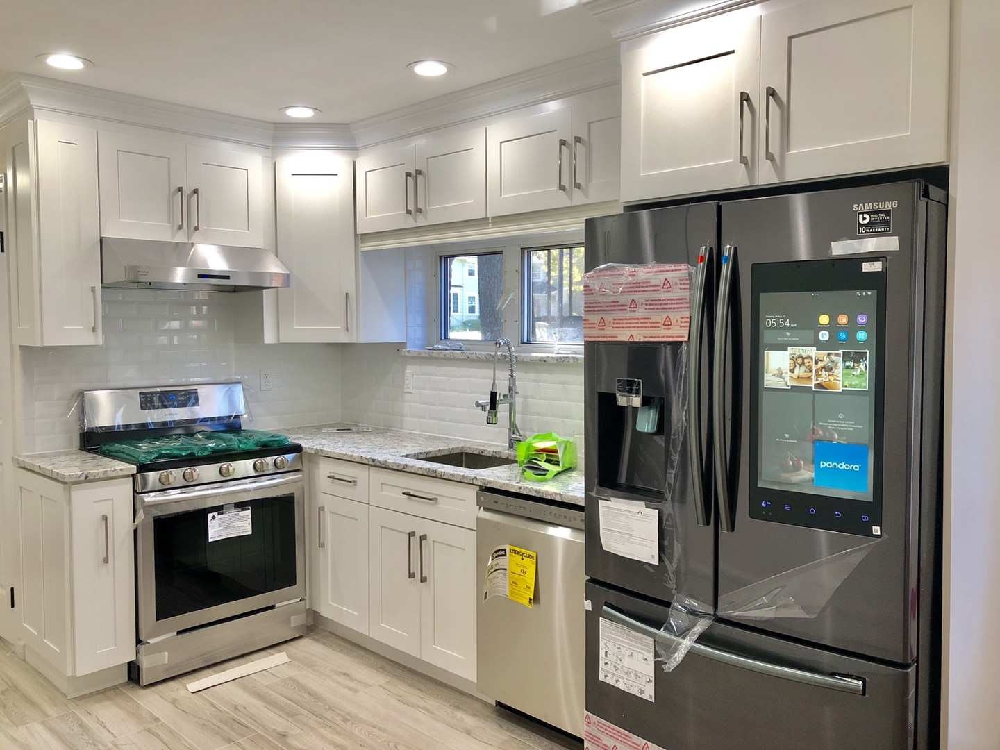 Modern kitchen featuring white cabinets, stainless steel appliances, and a digital Samsung refrigerator with a touchscreen.