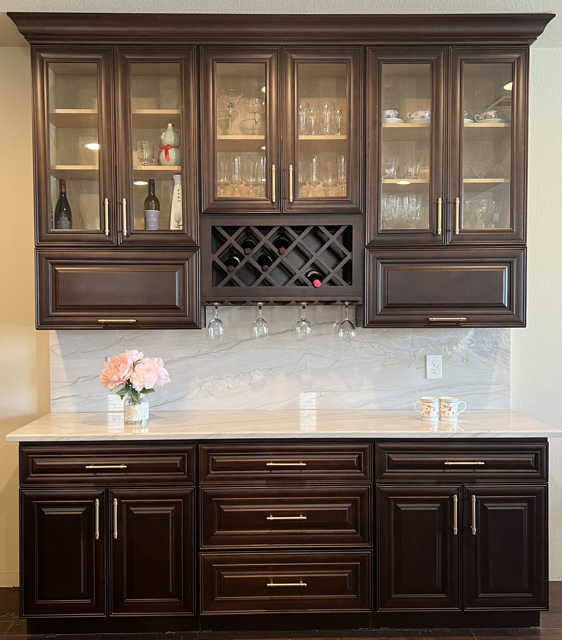 Elegant wooden cabinet display featuring glassware and wine bottles, with a marble countertop, showcasing a refined home bar setup.